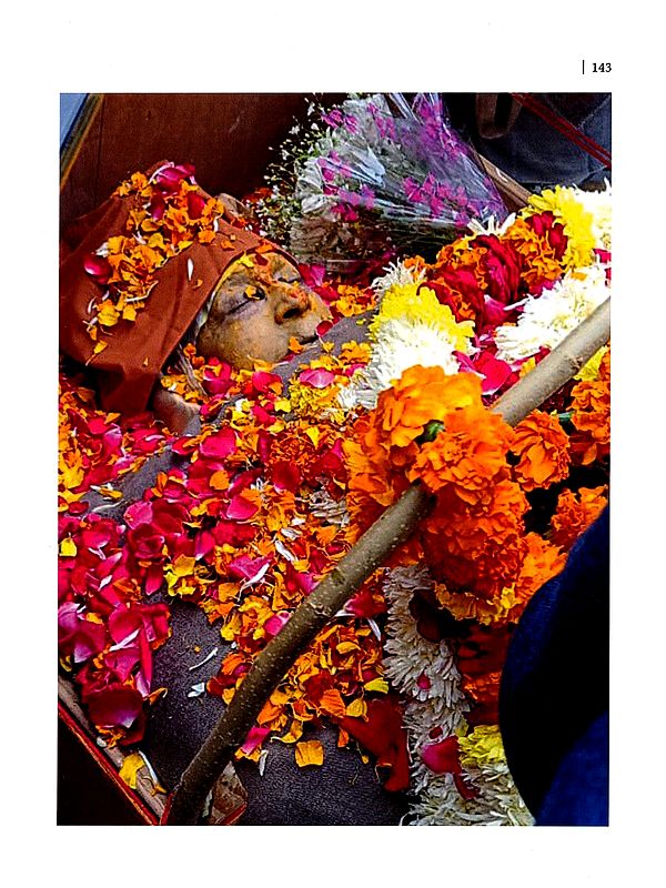 Temple offering page with garlands and flowers surrounding a decorated idol and staff