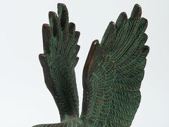 Green eagle sculpture with detailed feather texture and outstretched wings, brass patina finish