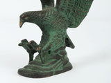 Close view of green Patna eagle sculpture: head, talons, and raised wing feather patterns