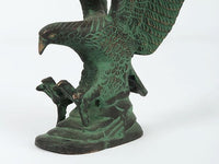 Close view of green Patna eagle sculpture: head, talons, and raised wing feather patterns