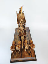 Ornate brass chariot sculpture with layered riders and vertical banner, on wooden base