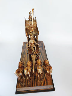 Ornate brass chariot sculpture with layered riders and vertical banner, on wooden base