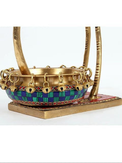 Close view of brass urli base with chain rim and colorful painted band across bowl