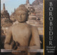 Dark stone Buddha statue with closed eyes and raised hands at the pyramid