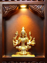 Gold-toned seated deity idol inside a carved brass frame niche