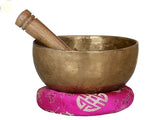 Tibetan brass singing bowl with wooden striker on pink patterned base, 6.5 cm