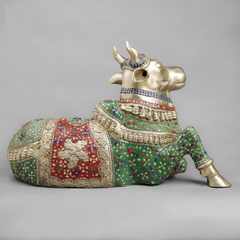 Seated Nandi brass sculpture from side view, floral patterned saddle and tail details