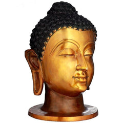 Brass Buddha head idol in three-quarter view, gold face with closed eyes