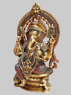 Brass Ganesha idol seated on throne, three-quarter view with jeweled attire