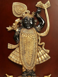 Brass deity wall hanging with black-faced figure and golden headpiece, mounted in frame