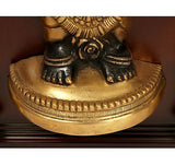 Close-up of brass deity base with black hands and gold ornament details, in frame