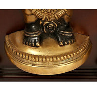 Close-up of brass deity base with black hands and gold ornament details, in frame