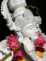 Krishna idol profile with gold flute, ornate crown, and pink flower garlands