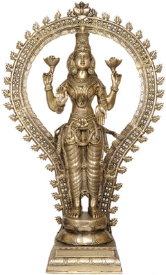 Brass Lakshmi statue with ornate halo and bejeweled draped outfit, standing on pedestal