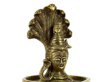 Shiva head and coiled serpent above, golden idol placed in shallow bowl tray