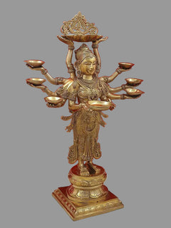 Brass ten-armed goddess statue with ornate crown and oil lamps, front three-quarter view.