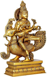 Gold brass Saraswati statue seated on peacock, holding a veena with detailed ornaments