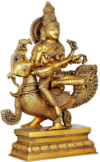 Gold brass Saraswati statue seated on peacock, holding a veena with detailed ornaments