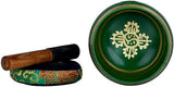 Tibetan singing bowl and wooden mallet; gold emblem on green brass surface