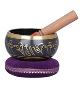 Dark blue singing bowl with gold mantras, wooden mallet, purple cushion