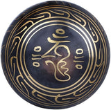 Singing bowl close-up: gold OM design on dark brass