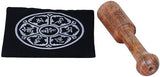 Black singing bowl on a mat with white circular pattern; wooden mallet with grip