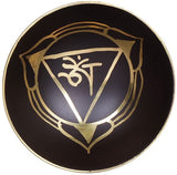 Black brass singing bowl with gold Om design on the surface and raised rim