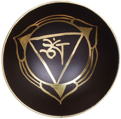 Black brass singing bowl with gold Om design on the surface and raised rim