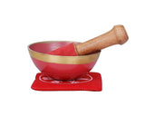 Brass Tibetan singing bowl with wooden mallet on red cushion