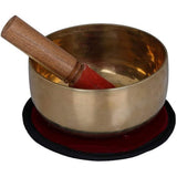 Brass Tibetan singing bowl with wooden mallet, on red and black cushion