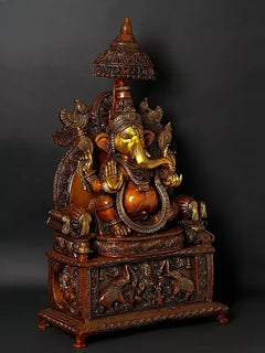 Brass Ganesha seated on detailed pedestal with multiple carved attendants, angled view